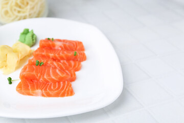 Fresh salmon sashimi with microgreens, wasabi and ginger on light tiled table, closeup. Space for text