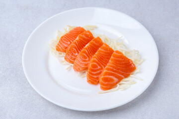Fresh salmon sashimi with sliced radish on light grey table, closeup