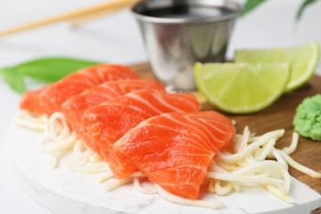 Fresh salmon sashimi with sliced radish on light table, closeup