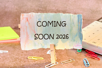 A decorative sign announces something is coming soon in 2026. A calendar and colorful paper clips suggest planning and anticipation for the upcoming event