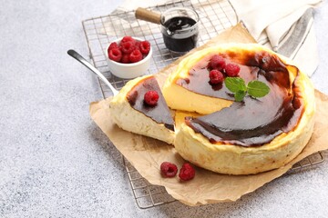 Tasty Basque cheesecake with raspberries and mint on light grey textured table. Space for text
