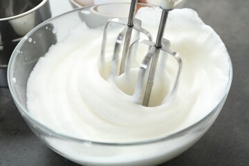 Beating egg whites with mixer at grey table, closeup
