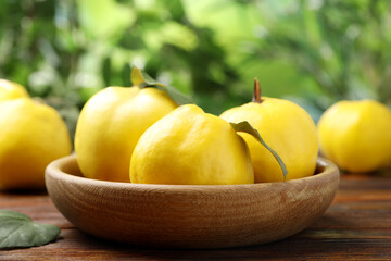 Fresh ripe quinces on wooden table outdoors, closeup