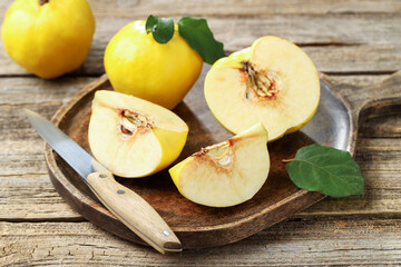 Ripe quinces and knife on wooden table, closeup