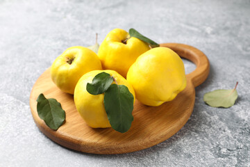 Ripe quinces and green leaves on grey table, closeup