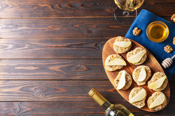 Tasty bruschettas with apples, honey, walnuts and white wine on wooden table, flat lay. Space for...