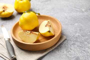 Fresh ripe quinces and knife on grey table, closeup. Space for text