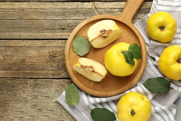 Whole and cut ripe quinces on wooden table, flat lay. Space for text