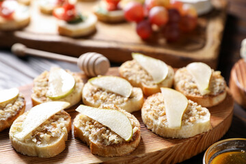 Tasty bruschettas with apples, honey and walnuts on wooden table, closeup