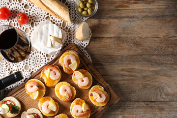 Flat lay composition with tasty bruschettas and red wine on wooden table. Space for text