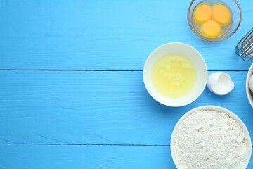 Broken eggs and products on blue wooden table, flat lay. Space for text