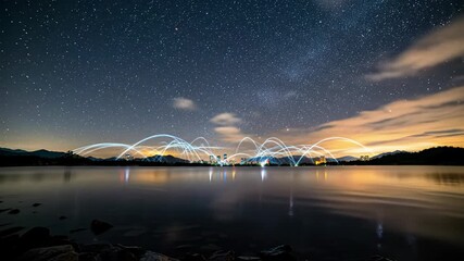Wide, low-angle panoramic tracking video at night of tranquil water reflecting a star-filled cosmic canopy. A distant smart city pulses with digital luminescence, symbolizing global data flow and - Powered by Adobe