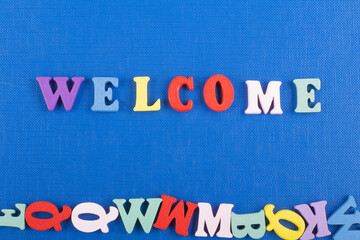 Fototapeta premium WELCOME word on blue background composed from colorful abc alphabet block wooden letters, copy space for ad text. Learning english concept.