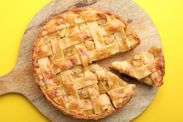 Delicious homemade apple pie on yellow background, top view