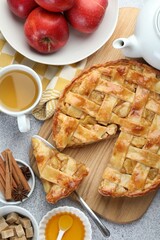 Delicious homemade pie, apples, spices and tea on grey textured table, flat lay