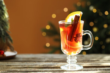 Tasty punch drink in glass on wooden table against brown background with blurred lights, space for text. Bokeh effect