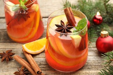 Tasty punch drink in glasses, spices and Christmas decor on wooden table, closeup