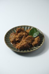 Beef rendang on rustic plate with white background. This is traditional food from West Sumatera, Indonesia. Made from beef, coconut milk and some herbs and spices