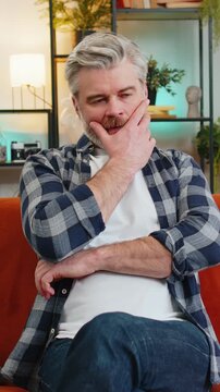 Disappointed old man sits at home reflecting on moral distress after quarrel break-up or divorce problem feeling bad annoyed ill sick. Sad middle-aged guy in room contemplates the emotional aftermath