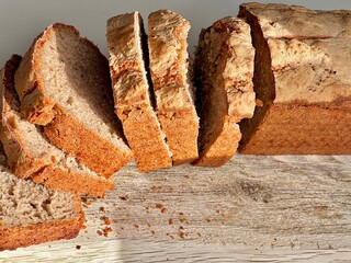 Bread loaf sourdough fermented food sliced homemade artisan crusty golden brown rustic fresh warm comfort breakfast brunch snack yeast cutting board crumbs wood grain natural light texture porous airy