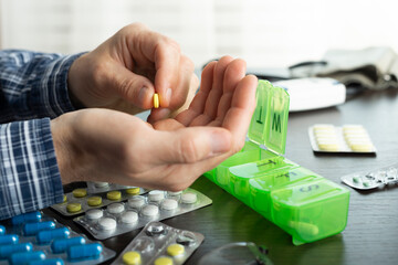 Middle aged caucasian man counts out pills for distributing scheduled dose of medication into pillbox