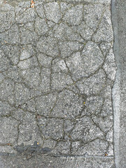 Cracked asphalt texture with visible cracks and imperfections on a city street