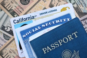 Social security number and California driving license with passport on US dollar money bills close up