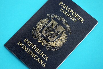 Dominican Republic passport book on light blue paper background close up. Travel document on blue...