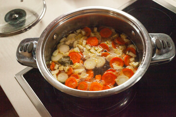 Overhead view of homemade vegetable broth cooking in a silver steel pot