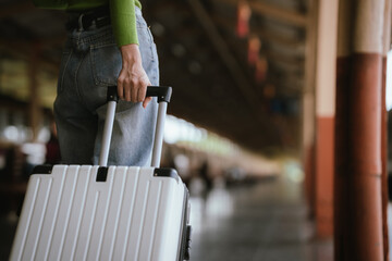 Fototapeta premium Traveler pulling a suitcase at a train station, representing travel, journey, transportation, and exploration.