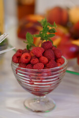 Fresh Raspberries in a Glass Bowl Garnished with Mint Leaves on a Bright Table Setting