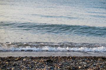 Wave in white foam on a pebble beach. Sea landscape.