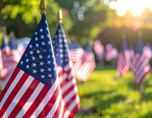 Close-up of American flags in a field with bokeh effect in the background. Sunlight filters through trees. Celebratory and patriotic