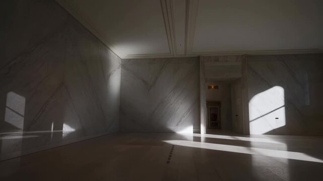 Soft shadows create beautiful patterns on the marble walls of an empty hall in the afternoon light. The serene atmosphere invites calm reflection and appreciation of design