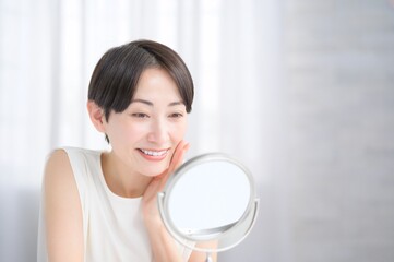 鏡を見て肌を確認する日本人女性