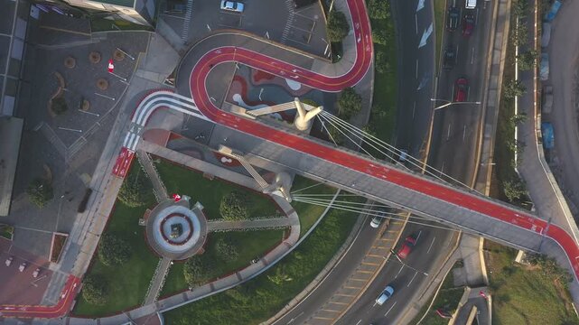 Drones perspective flying over a modern red bike lane, pedestrian bridge and city highway traffic