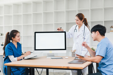 Obraz premium Young medical team discussing patient data at desk with blank monitor, collaborative healthcare planning and friendly communication