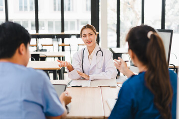 Fototapeta premium Young female doctor consulting with two colleagues in modern clinic, friendly confident expression