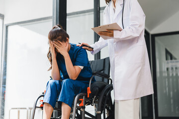 Doctor consoling sad patient in wheelchair, Woman crying in hospital after receiving bad news or diagnosis