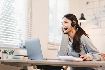 Obraz premium Young woman wearing headset smiling during remote customer service call in bright home office
