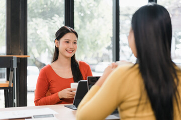 Young woman smiling while holding coffee cup in cafe during friendly conversation