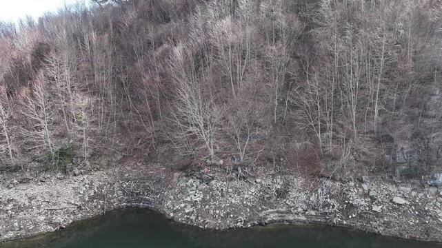 Drone flies across Kido Dam lake, moving left as trees clear to reveal the massive dam ahead. A calm yet dramatic shot perfect for nature, travel, or cinematic stock footage.