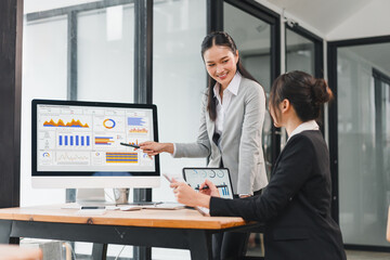 Businesswomen analyzing sales dashboard and charts in modern office, collaborative meeting with digital analytics and presentation