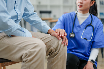 Male patient and female nurse holding hands in clinic showing compassionate care and support during...