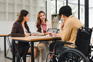 Diverse business team in meeting, woman presents data on tablet to colleague in wheelchair at inclusive office