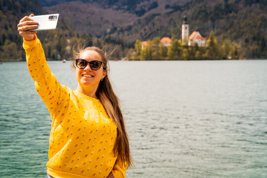 Turista entusiasmada recorriendo el Lago Bled, tomandose una Selfie frente a sus aguas