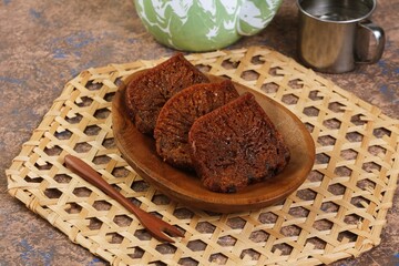 Close-up of traditional Indonesian caramel sponge cake, known as bolu karamel or honeycomb cake, served on a wooden plate with natural texture and warm lighting.