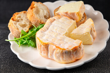 Washed rind cheese soft cheese with orange rind munster french cheese tasty snack fresh delicious gourmet food background on the table rustic top view copy space