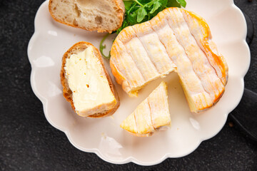 Washed rind cheese soft cheese with orange rind munster french cheese tasty snack fresh delicious gourmet food background on the table rustic top view copy space