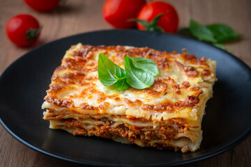 Portion of ground beef lasagna topped with melted cheese and garnished with fresh parsley served on a plate in close view for a menu